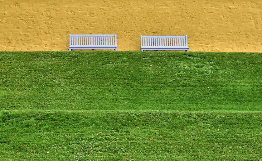 Bancs en bois sur une pelouse contre un mur jaune Bancs en bois sur une pelouse contre un mur jaune
