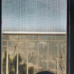 Vue à travers une moustiquaire d'une fenêtre sur un balcon et des arbres
