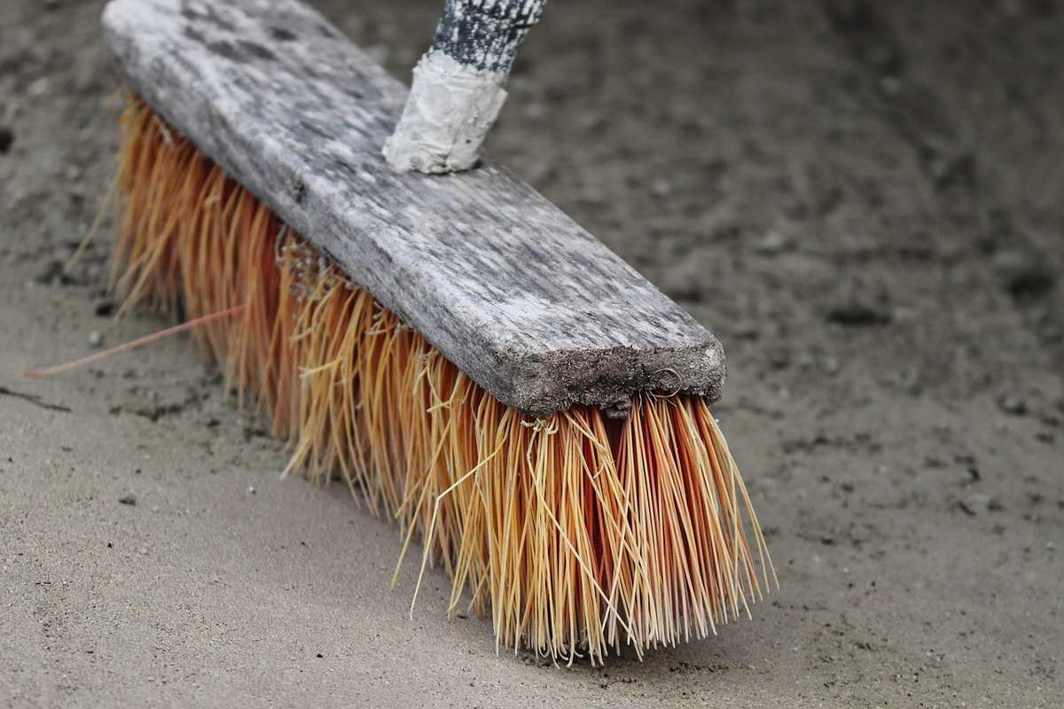 Balai à poils jaunes sur surface grise, manche attaché