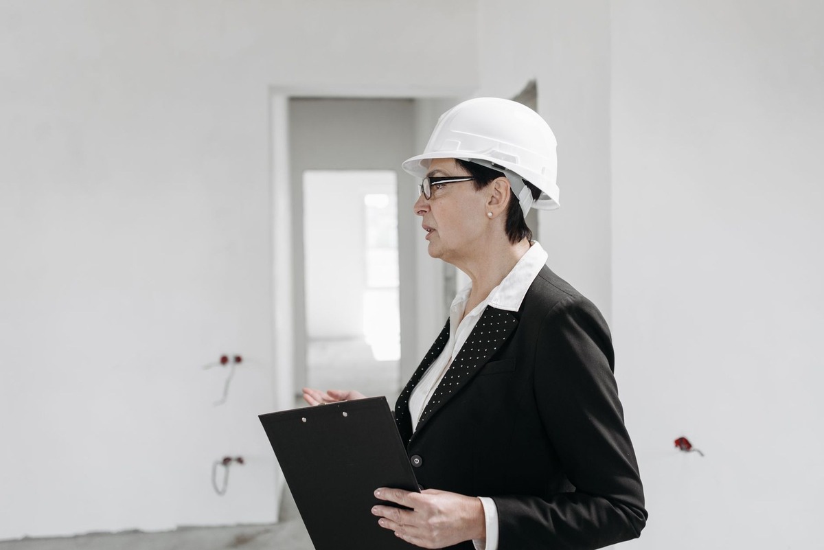 Femme en tenue professionnelle inspecte un bâtiment en construction avec un classeur