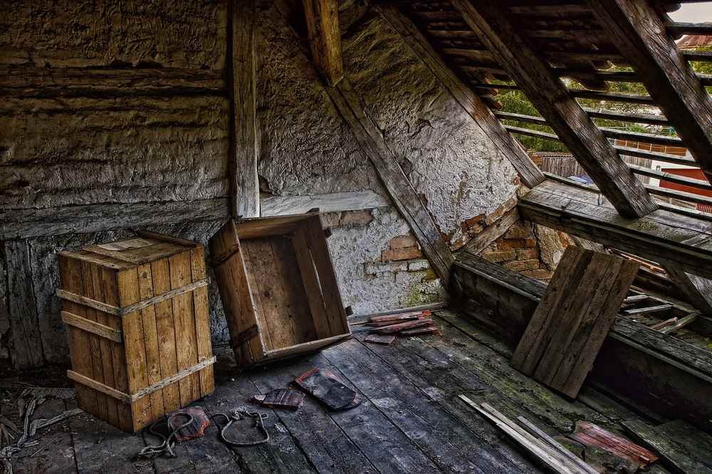 Ancien grenier avec caisses en bois, planches et poutres décayantes