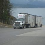 Camion blanc avec deux remorques sur route près d'une baie