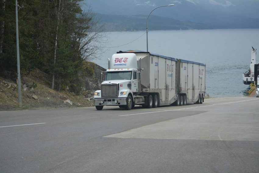 Camion blanc avec deux remorques sur route près d'une baie